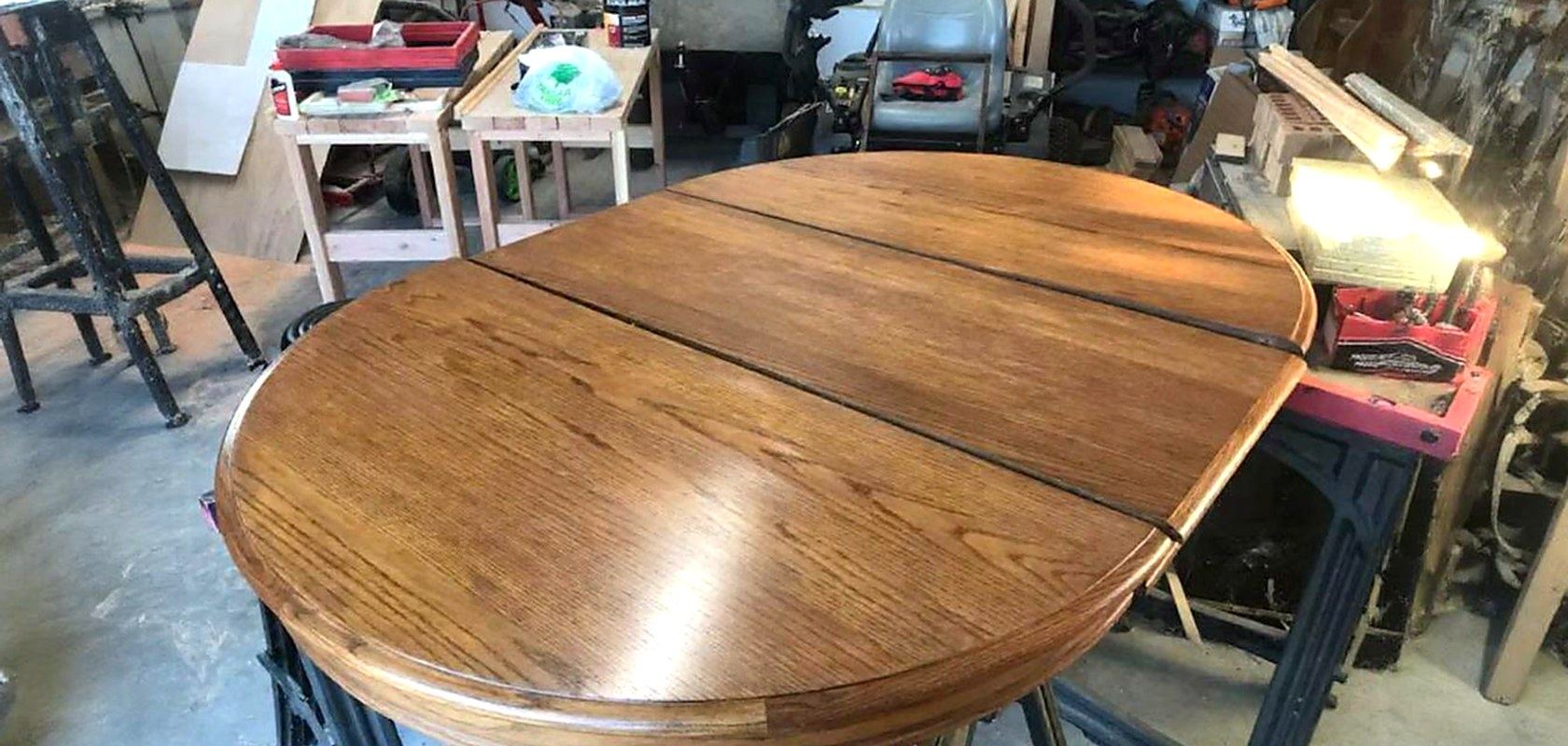 An oval oak dining table with its leaves in, refinished in the Grace Woodwork shop