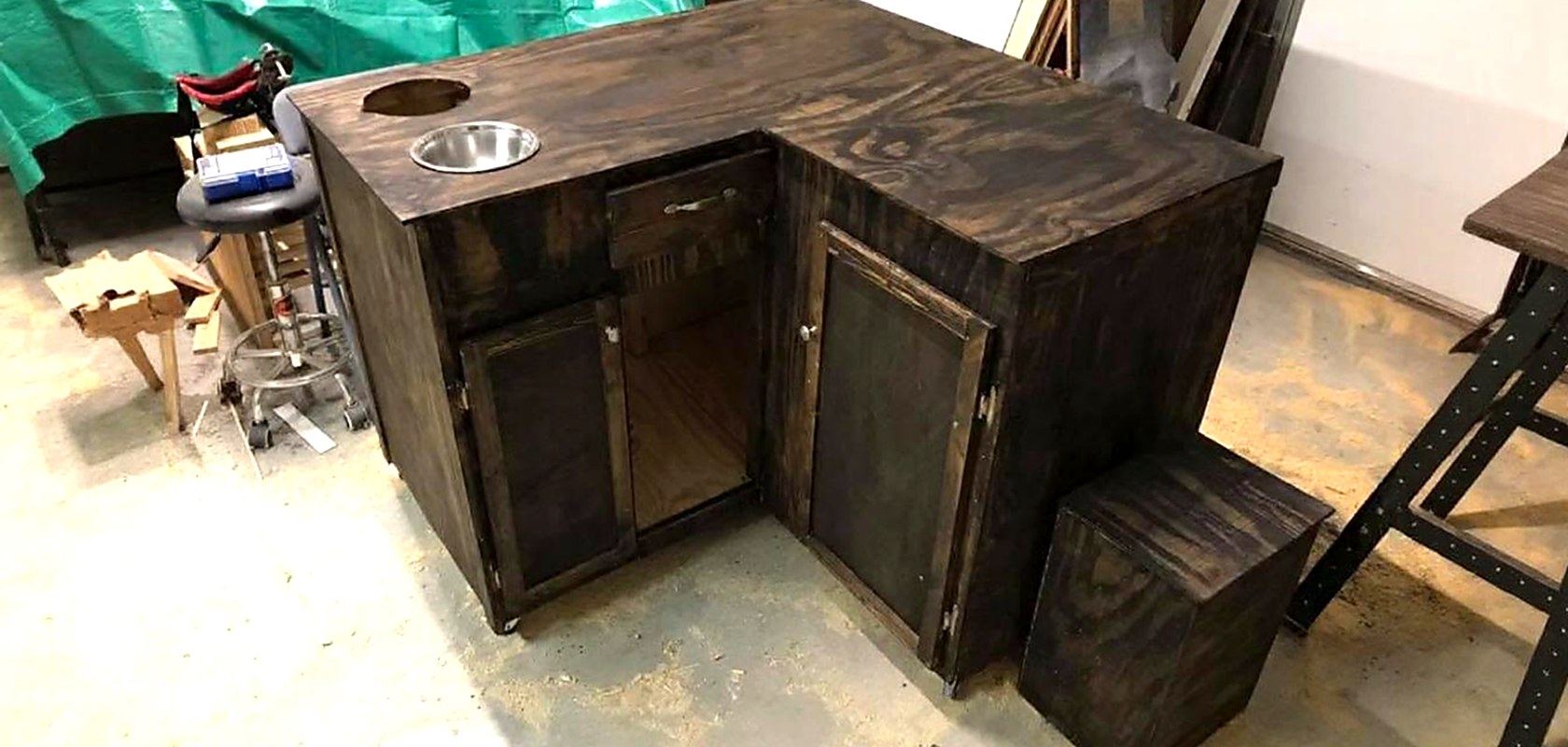 A dark stained corner bar cabinet with a built-in ice bucket